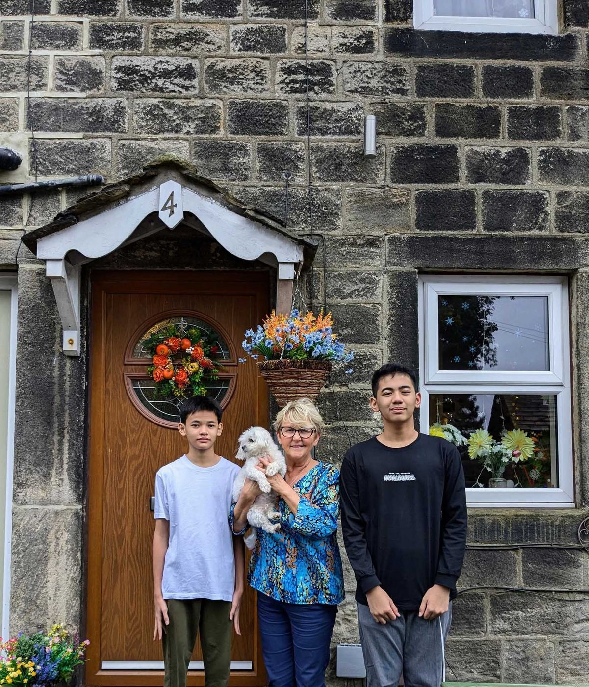 A host mother with two students and the family dog outside their home